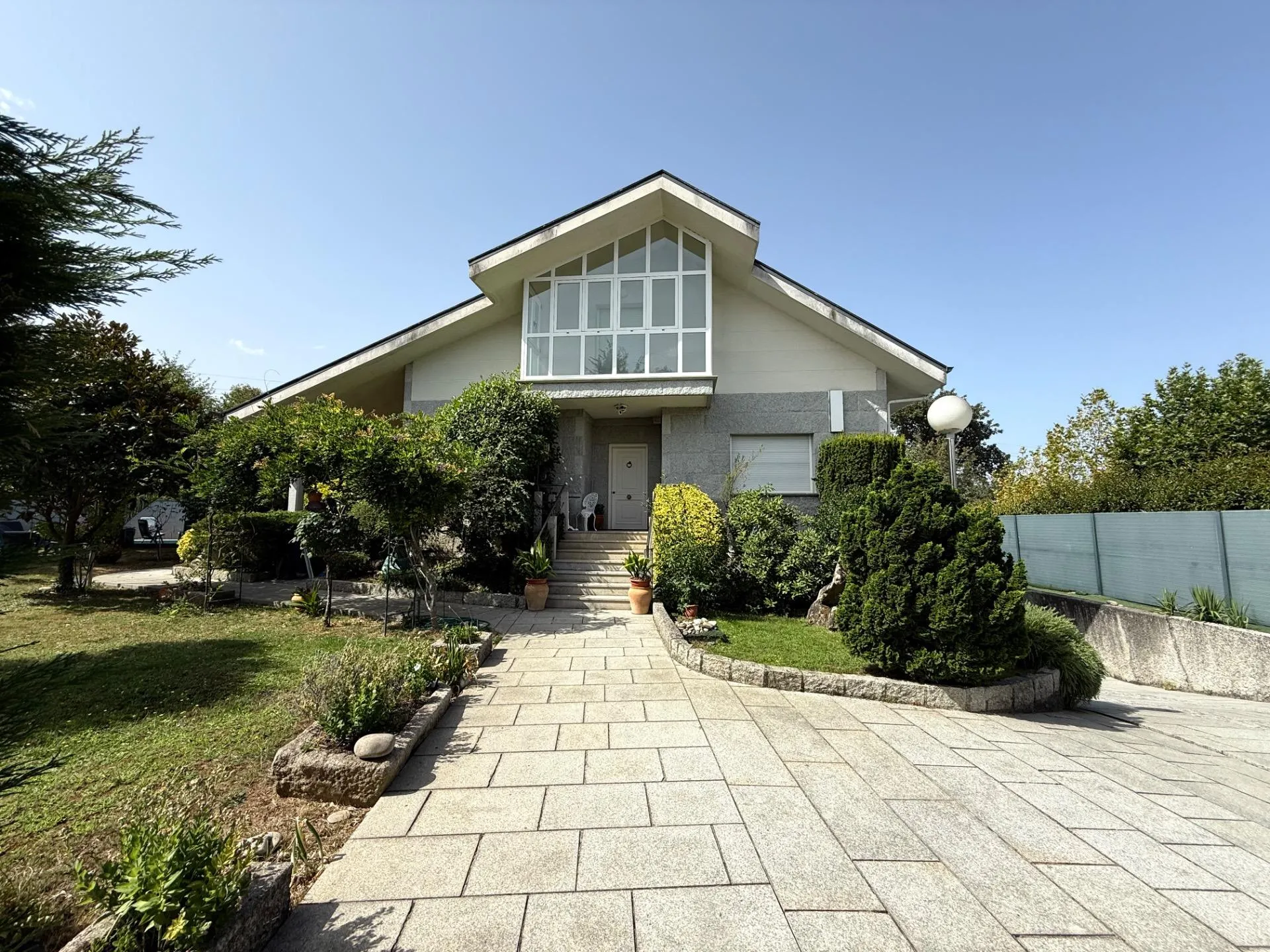 Fachada frontal con jardín maduro