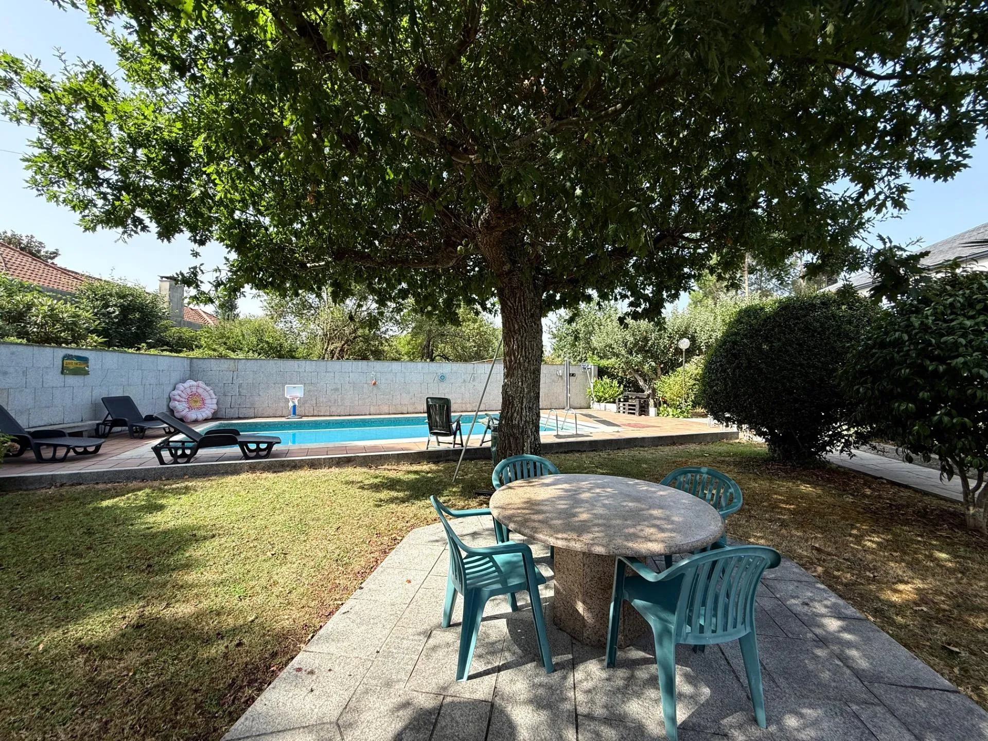 Jardín con comedor exterior bajo árbol centenario